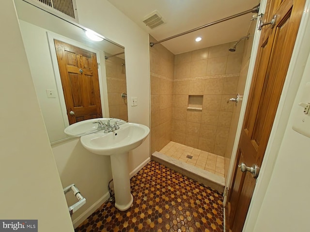 bathroom featuring tiled shower and sink