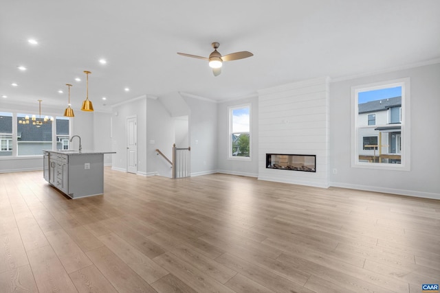 unfurnished living room with ornamental molding, a large fireplace, light hardwood / wood-style floors, and ceiling fan