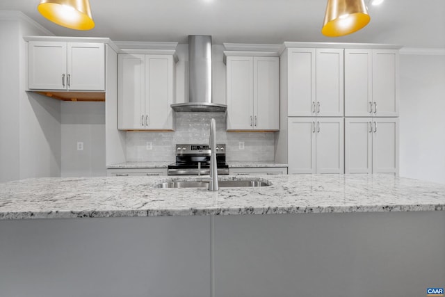 kitchen featuring white cabinets, wall chimney exhaust hood, crown molding, and decorative light fixtures