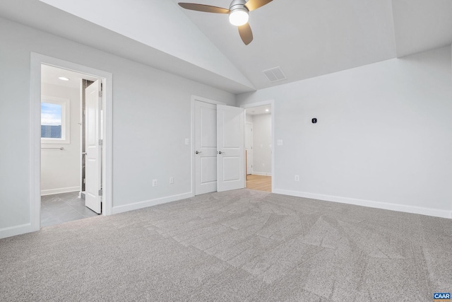 unfurnished bedroom featuring ensuite bath, ceiling fan, vaulted ceiling, and light colored carpet