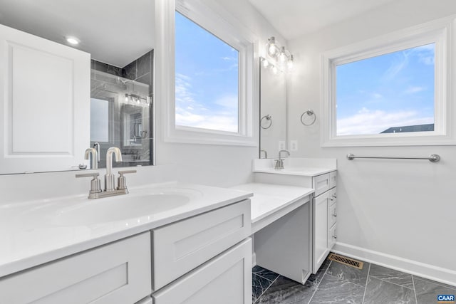 bathroom with a tile shower, vanity, and a healthy amount of sunlight