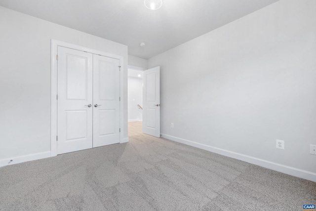 unfurnished bedroom featuring light colored carpet and a closet