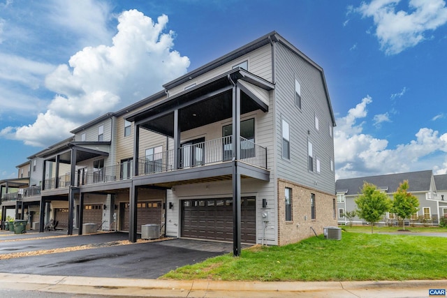 exterior space featuring a balcony, a front lawn, central AC unit, and a garage