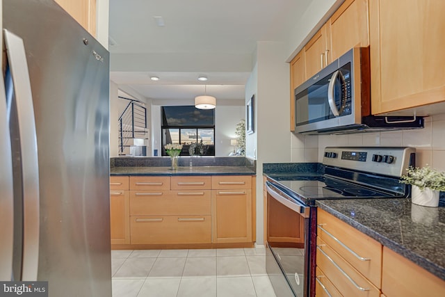 kitchen featuring tasteful backsplash, appliances with stainless steel finishes, dark stone countertops, light tile patterned flooring, and decorative light fixtures