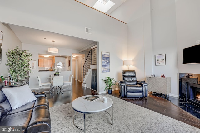 living room with wood-type flooring, a high ceiling, and a premium fireplace