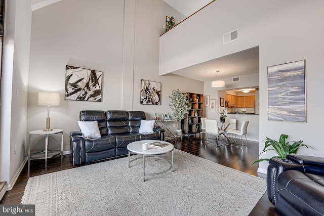 living room with a towering ceiling and dark hardwood / wood-style floors