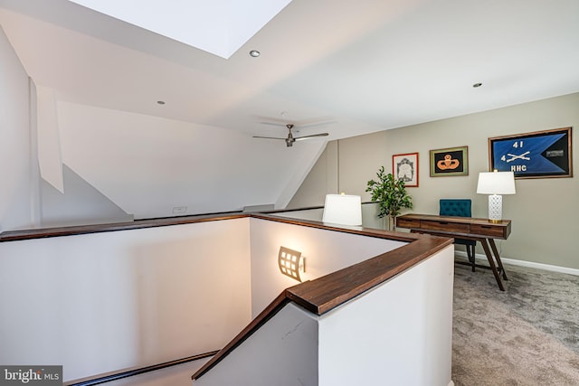 hallway with light carpet and lofted ceiling with skylight