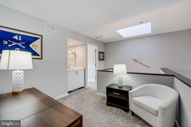 sitting room featuring sink, light colored carpet, and a skylight