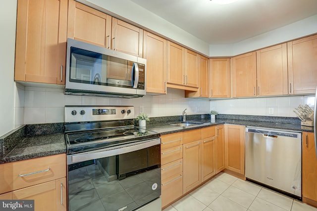 kitchen featuring appliances with stainless steel finishes, decorative backsplash, dark stone countertops, and sink