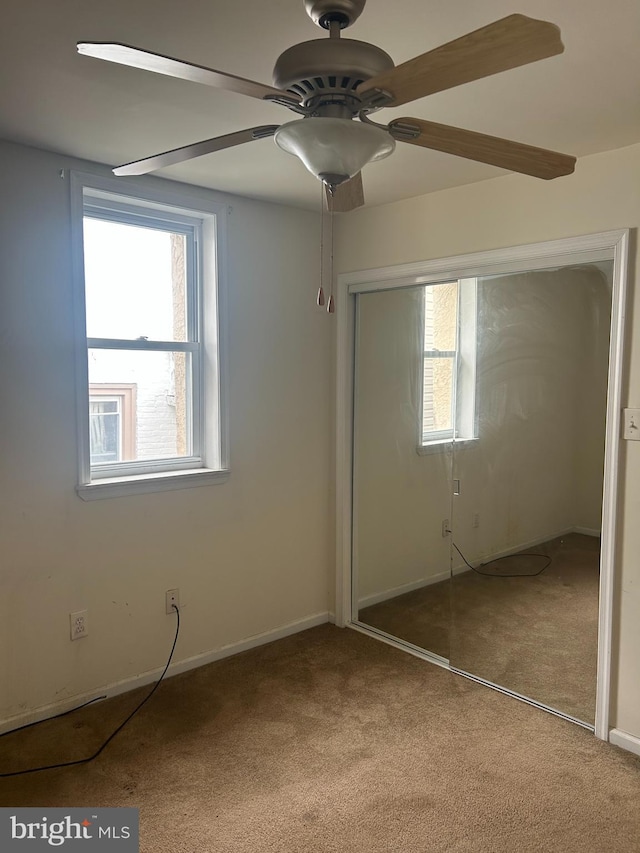 unfurnished bedroom with carpet flooring, a closet, multiple windows, and ceiling fan