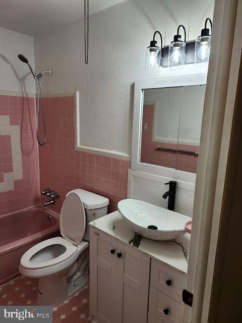 full bathroom featuring tile walls, vanity, toilet, and tiled shower / bath