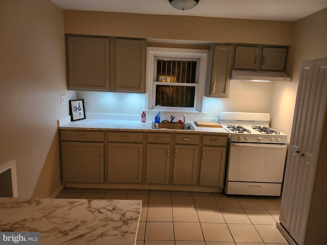 kitchen with white gas range, sink, light tile patterned floors, and gray cabinets