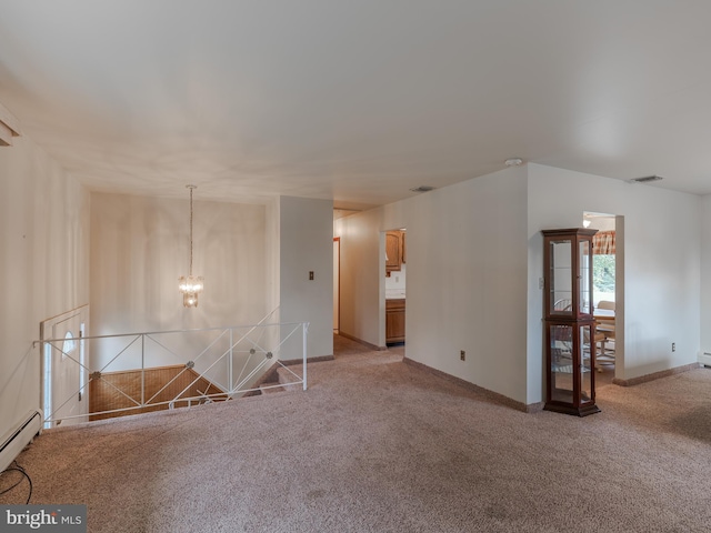 spare room featuring a baseboard heating unit, a chandelier, and carpet