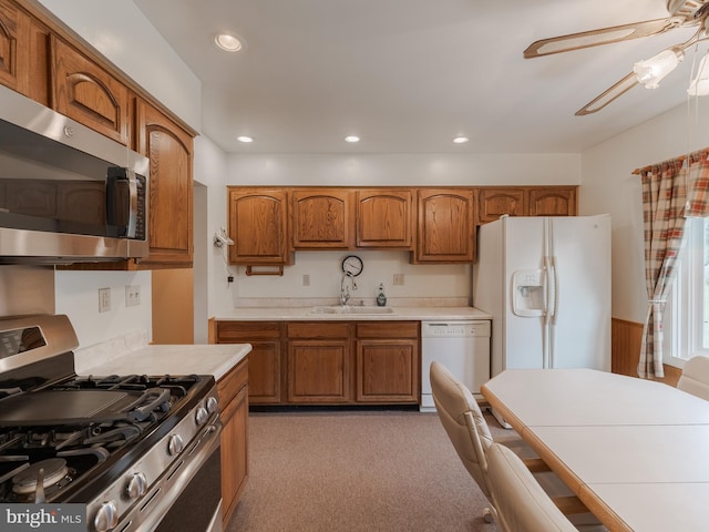 kitchen with sink, light carpet, stainless steel appliances, and ceiling fan