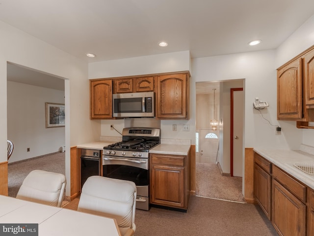 kitchen featuring dark carpet, a notable chandelier, appliances with stainless steel finishes, and hanging light fixtures