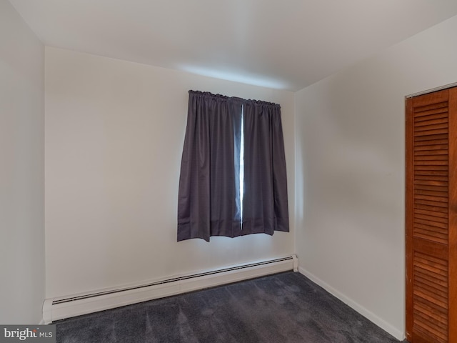 empty room with dark carpet and baseboard heating