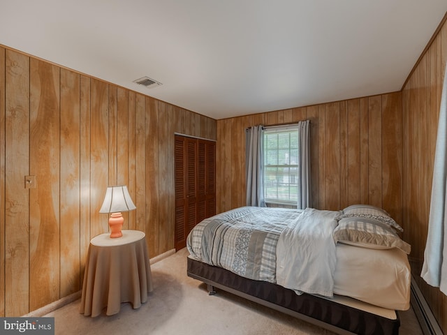 bedroom featuring a baseboard radiator, wooden walls, a closet, and carpet