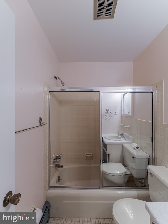 full bathroom with enclosed tub / shower combo, vanity, and toilet