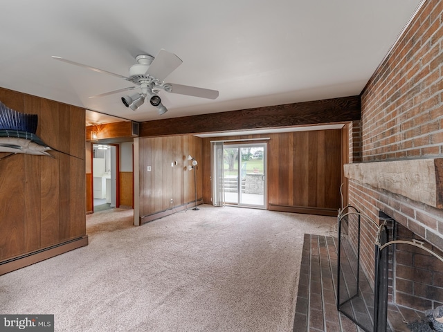 unfurnished living room featuring carpet floors, wooden walls, and a fireplace