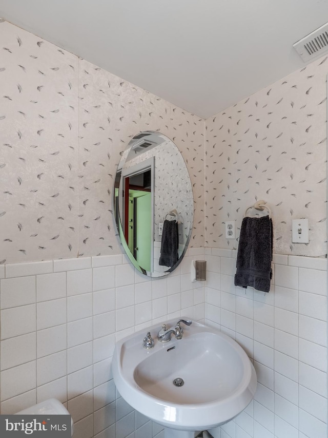 bathroom featuring tile walls and sink