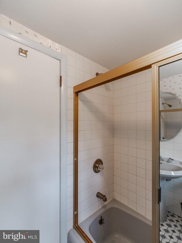 bathroom featuring tile walls, tiled shower / bath, and sink