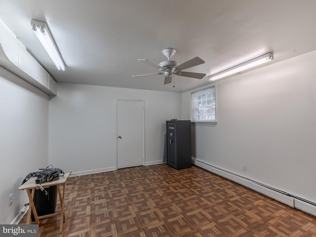 basement with a baseboard radiator, ceiling fan, and dark parquet flooring