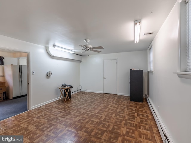 basement featuring ceiling fan, baseboard heating, white fridge, and dark parquet flooring