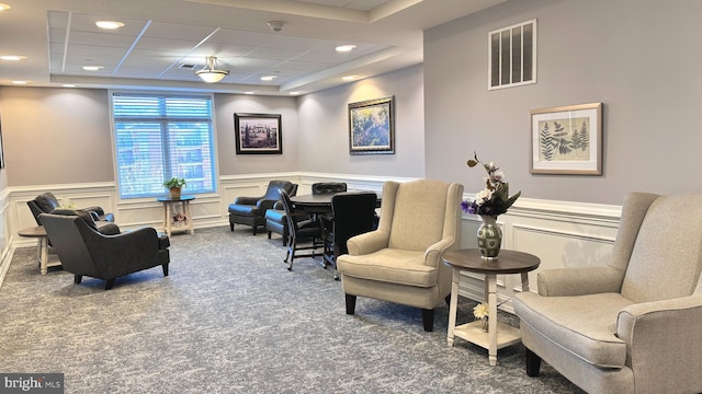 living area with a raised ceiling and carpet floors