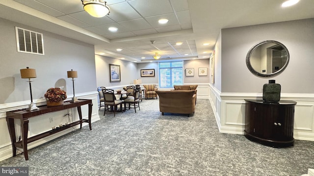 carpeted living room featuring a drop ceiling