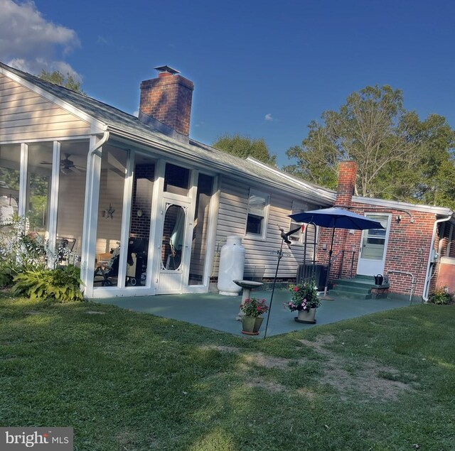 back of property with a lawn and a patio area