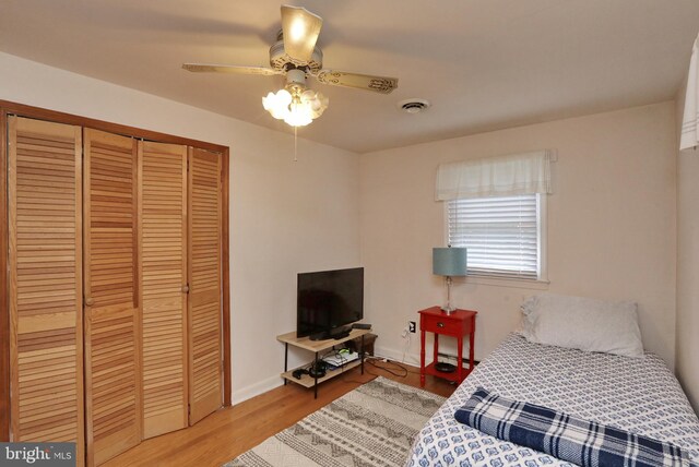 bedroom featuring wood-type flooring, a closet, baseboard heating, and ceiling fan