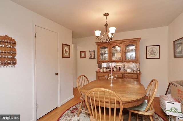 dining space featuring light wood-type flooring and an inviting chandelier