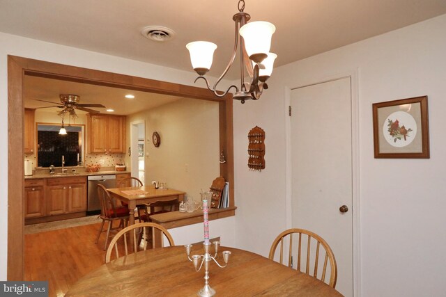 dining room featuring sink, ceiling fan with notable chandelier, and light hardwood / wood-style floors