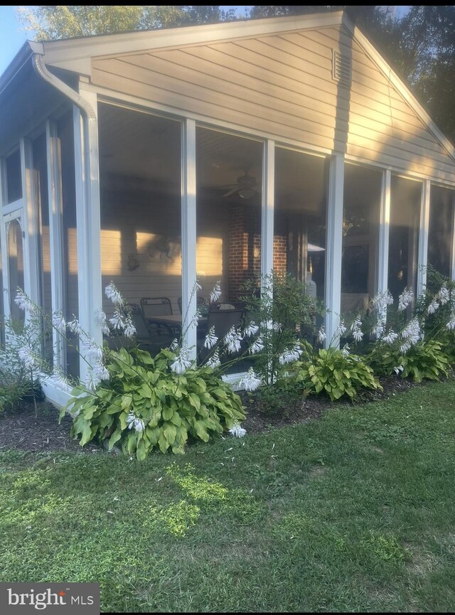 view of side of home with a sunroom and a lawn