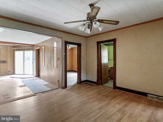 unfurnished room featuring ceiling fan, hardwood / wood-style flooring, wood walls, and ornamental molding