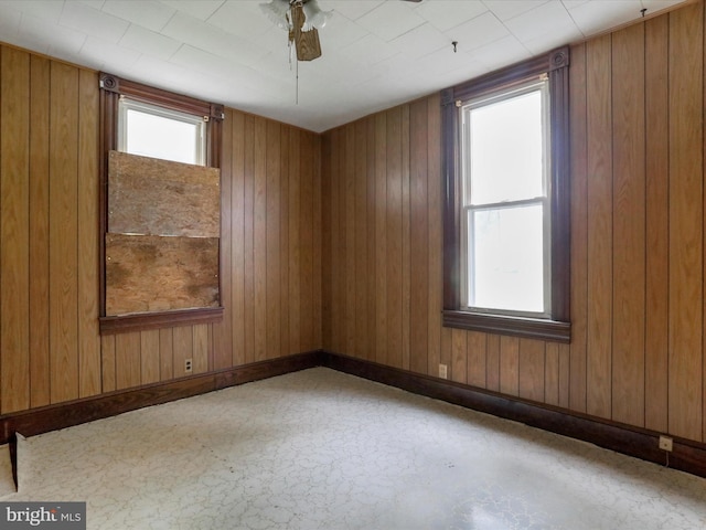 spare room with ceiling fan and wood walls