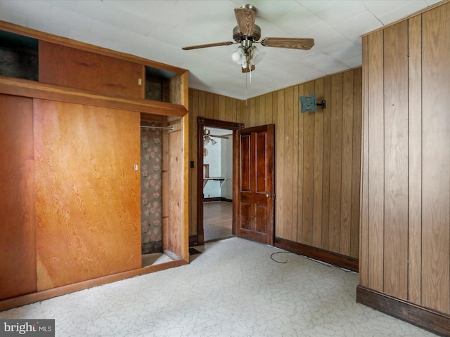 unfurnished bedroom featuring wooden walls and ceiling fan