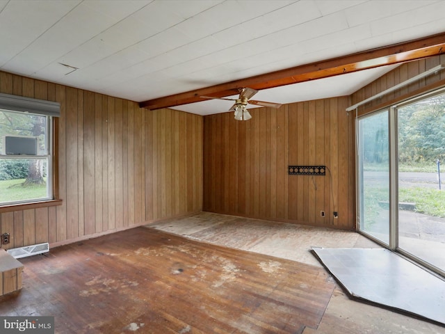 unfurnished room featuring wood walls, beam ceiling, dark hardwood / wood-style flooring, and a wealth of natural light