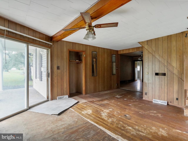 empty room with wood walls, beam ceiling, and dark wood-type flooring