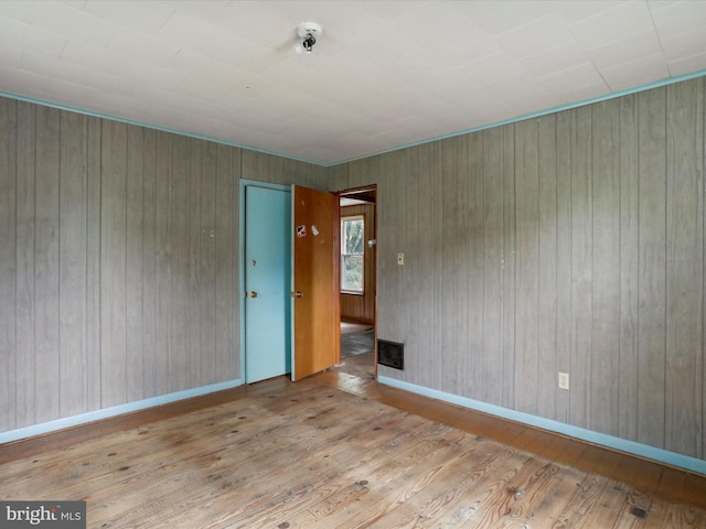 unfurnished room featuring wooden walls and light wood-type flooring