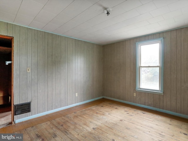 unfurnished room featuring wooden walls and light hardwood / wood-style flooring