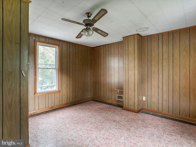 spare room featuring ceiling fan and wooden walls