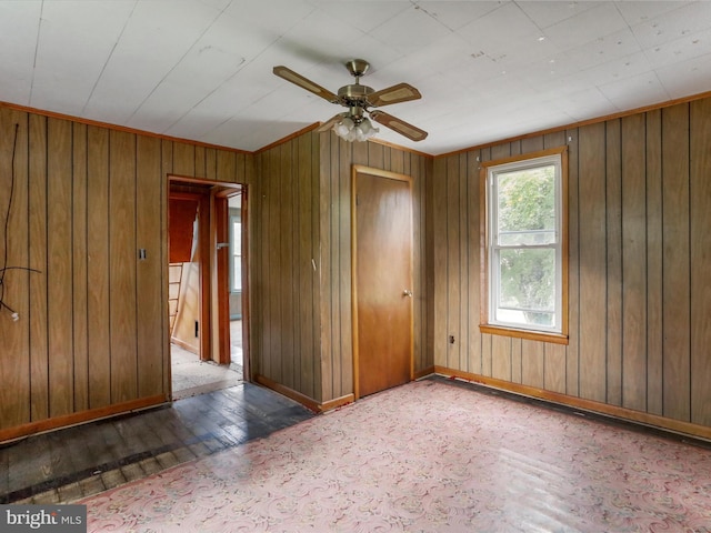 empty room featuring wood-type flooring, ceiling fan, and wooden walls