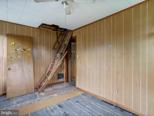 interior space featuring ceiling fan and wood walls