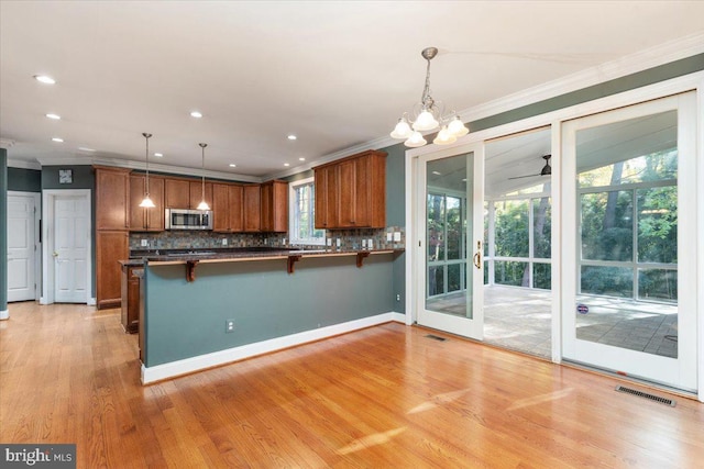 kitchen with a kitchen breakfast bar, kitchen peninsula, a healthy amount of sunlight, and decorative light fixtures