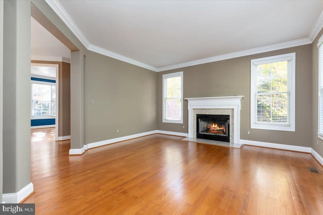 unfurnished living room with light hardwood / wood-style floors, a healthy amount of sunlight, and crown molding