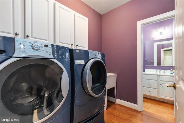 laundry room with light hardwood / wood-style floors, cabinets, and independent washer and dryer