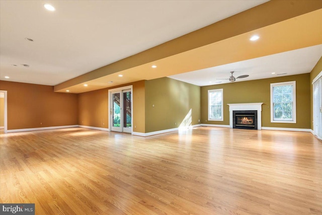 unfurnished living room featuring light wood-type flooring, plenty of natural light, and ceiling fan