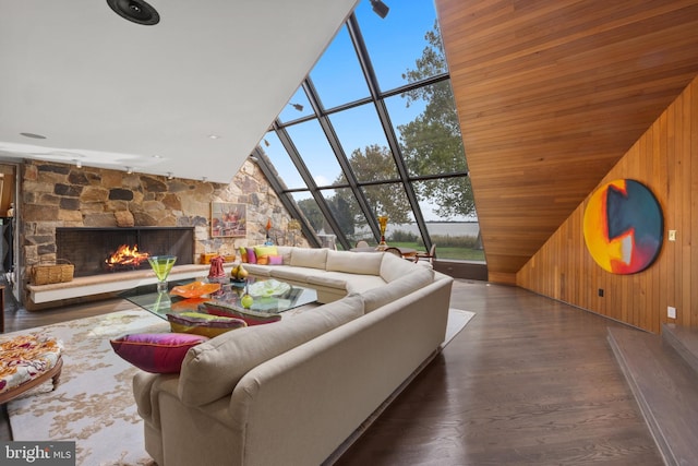 living room with a stone fireplace, wooden walls, high vaulted ceiling, and dark hardwood / wood-style floors