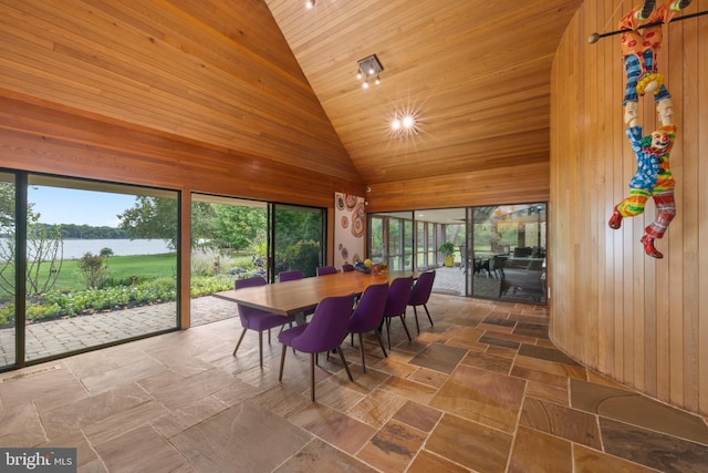 dining space featuring wood walls, a water view, and wood ceiling